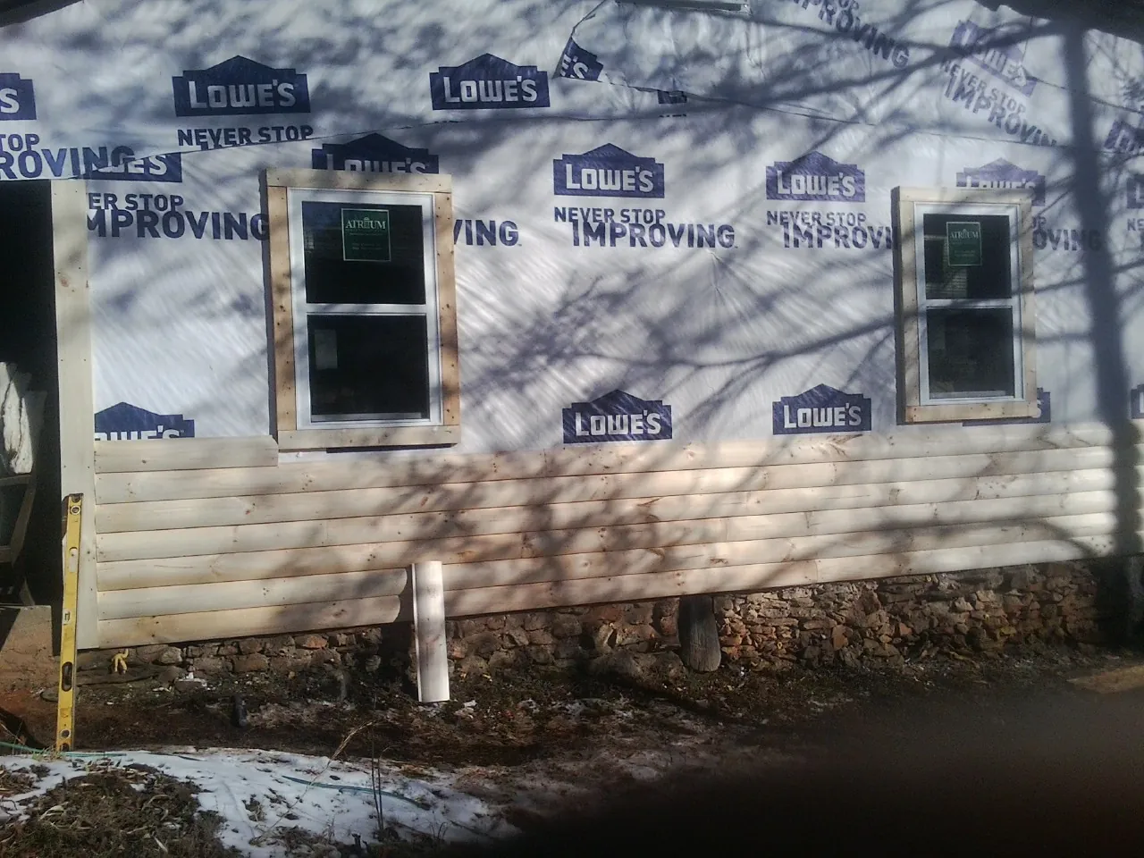 House wrap and new log siding going up on an exterior wall in Poplar Branch
