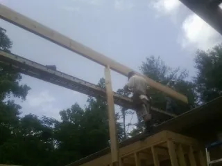 Carpenter setting a ridge beam over a new addition frame — Ice Dam Removal by Roofing Brothers in Poplar Branch