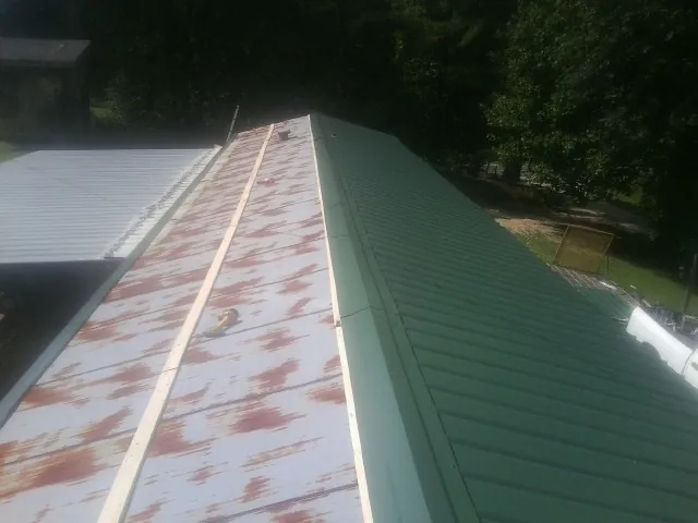 Old rusted panels beside newly installed green metal roofing — Wind Damage Roof Repair by Roofing Brothers in Poplar Branch