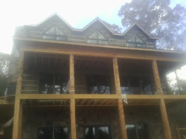 Dormers and porch framing on a large log home under construction — Roof Coating work by our crew in Poplar Branch
