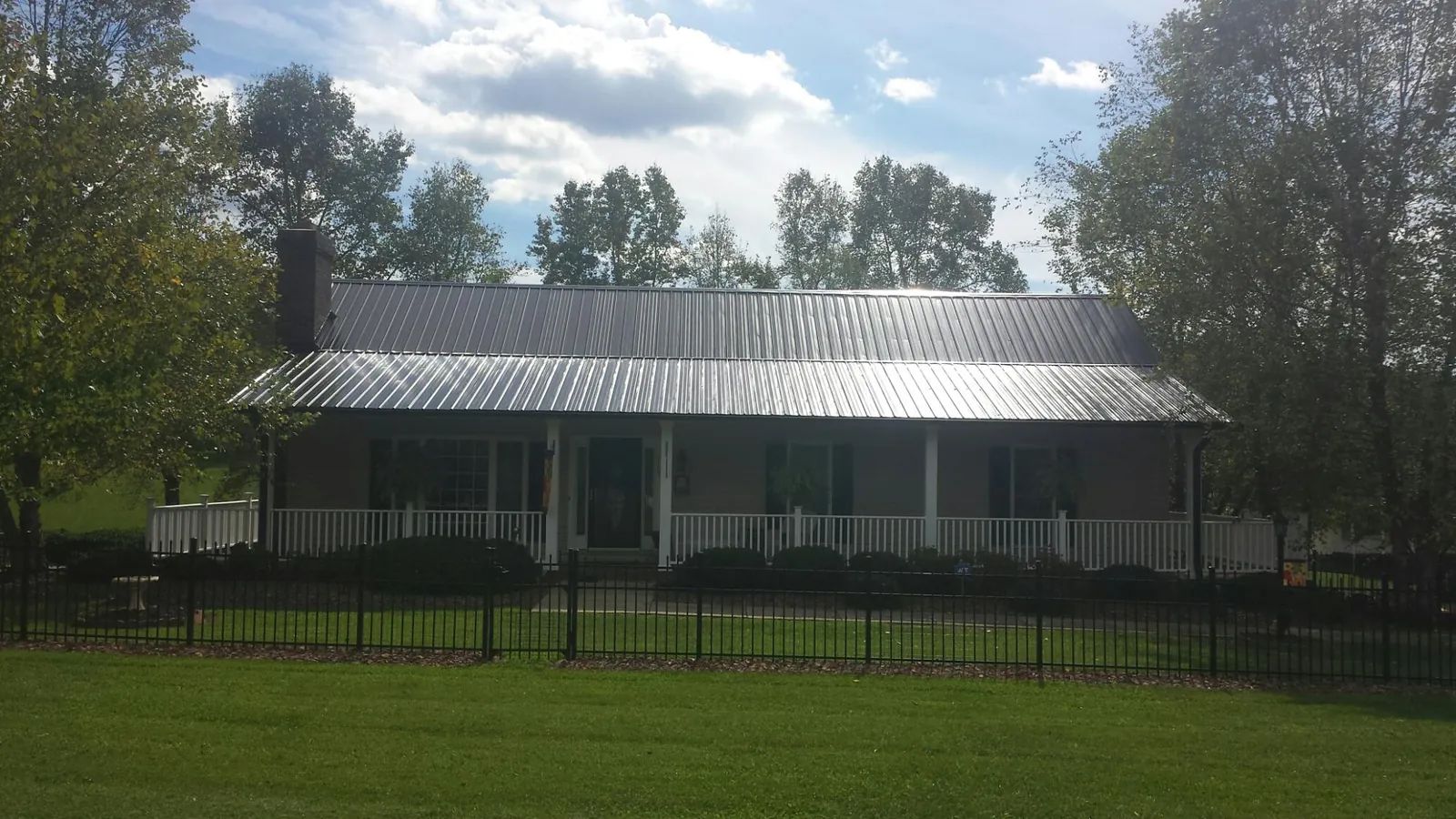 Gray metal roof on a brick ranch with a full width front porch — Gutter Guard Installation work by our crew in Poplar Branch