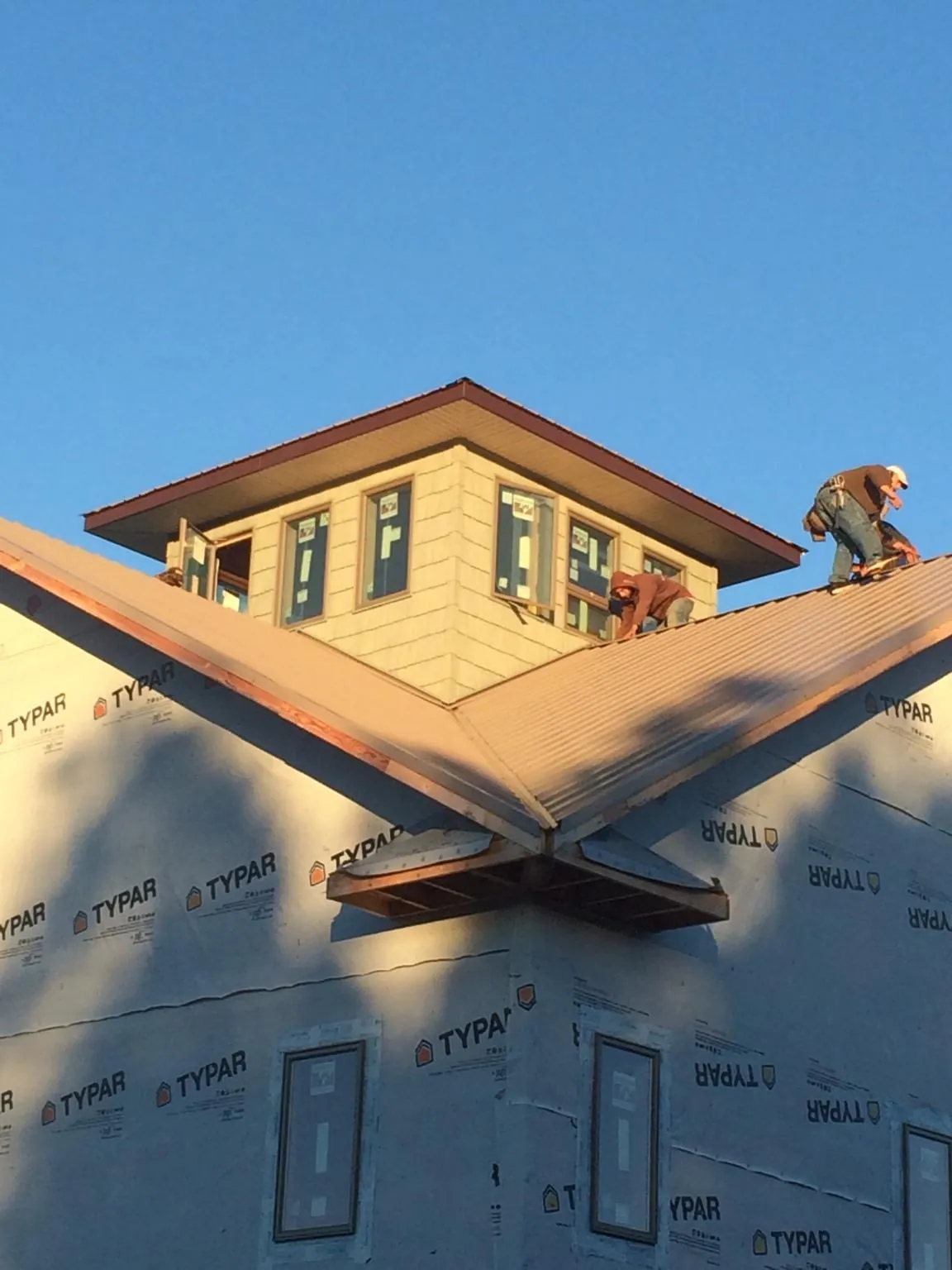 Roofers working around a rooftop cupola on a new metal roof at sunset — Roof Waterproofing in Poplar Branch by Roofing Brothers